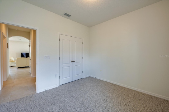 unfurnished bedroom with light colored carpet and a closet