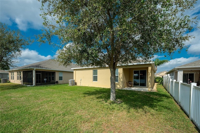 back of house featuring cooling unit, a lawn, and a sunroom