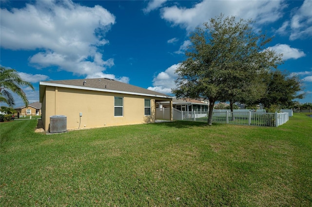 back of property with central air condition unit and a lawn