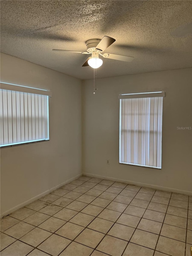 spare room featuring ceiling fan, a textured ceiling, and light tile patterned floors