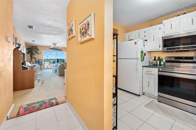 kitchen featuring light tile patterned floors, stainless steel appliances, white cabinetry, and a textured ceiling