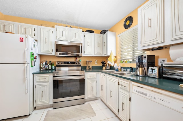 kitchen with stainless steel appliances, a textured ceiling, white cabinets, light tile patterned flooring, and sink