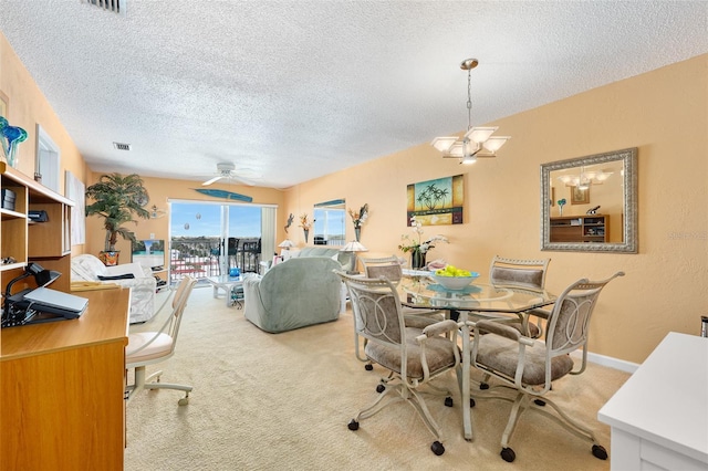 dining room featuring a textured ceiling, light carpet, and ceiling fan with notable chandelier