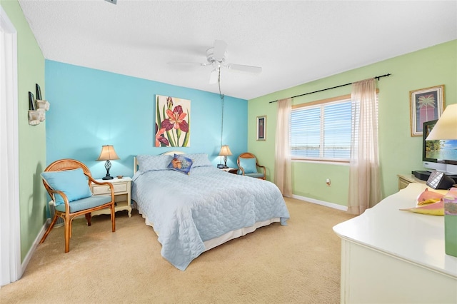 bedroom featuring ceiling fan, light carpet, and a textured ceiling