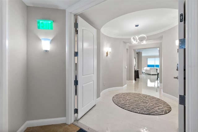 hallway featuring a chandelier, marble finish floor, and baseboards