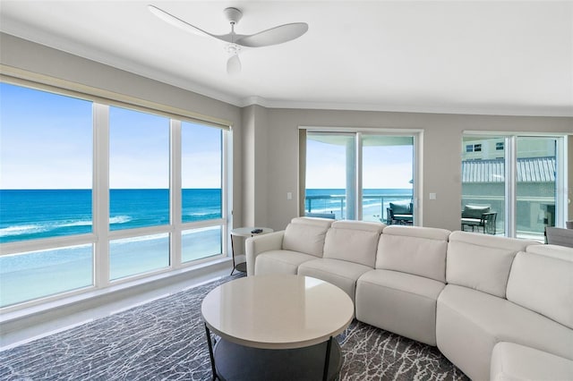 living area with ornamental molding, a water view, and a ceiling fan