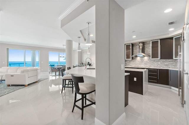 kitchen with dark brown cabinetry, wall chimney range hood, modern cabinets, and a breakfast bar