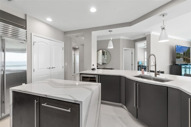 kitchen featuring wine cooler, built in refrigerator, a kitchen island, a sink, and pendant lighting