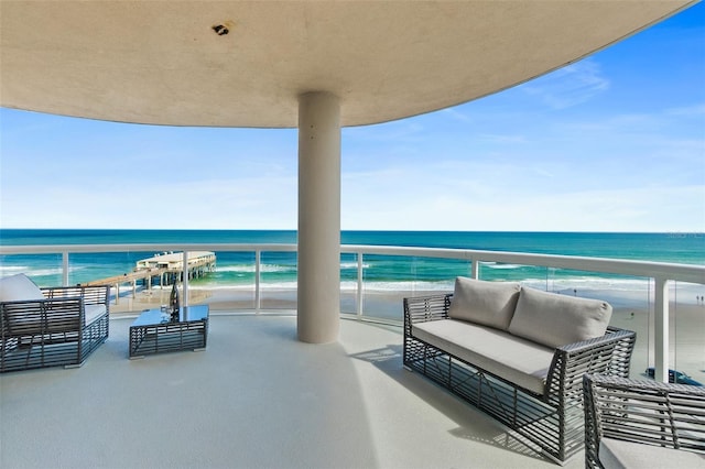 balcony with a water view, a beach view, and an outdoor living space