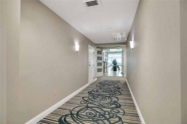 hall featuring baseboards, visible vents, and carpet flooring