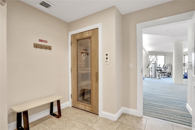 hall featuring light tile patterned floors, light colored carpet, visible vents, and baseboards