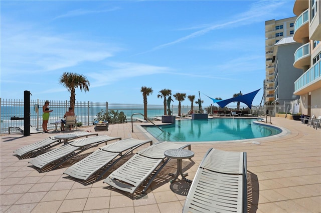 pool with a water view, a patio area, and fence