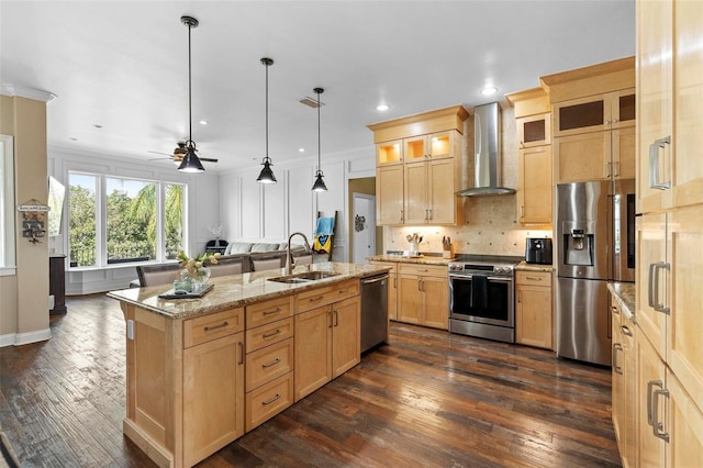 kitchen featuring a center island with sink, light stone countertops, sink, appliances with stainless steel finishes, and wall chimney exhaust hood