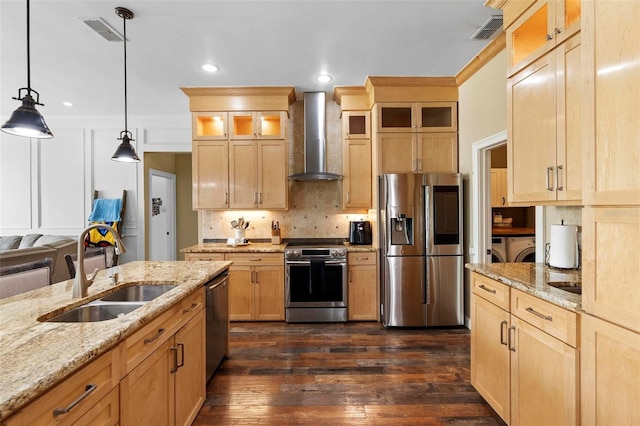 kitchen featuring sink, light stone counters, pendant lighting, stainless steel appliances, and wall chimney exhaust hood