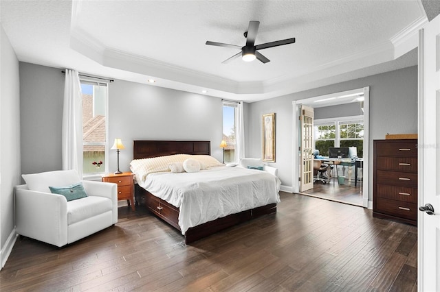 bedroom with a tray ceiling, dark wood-type flooring, and multiple windows