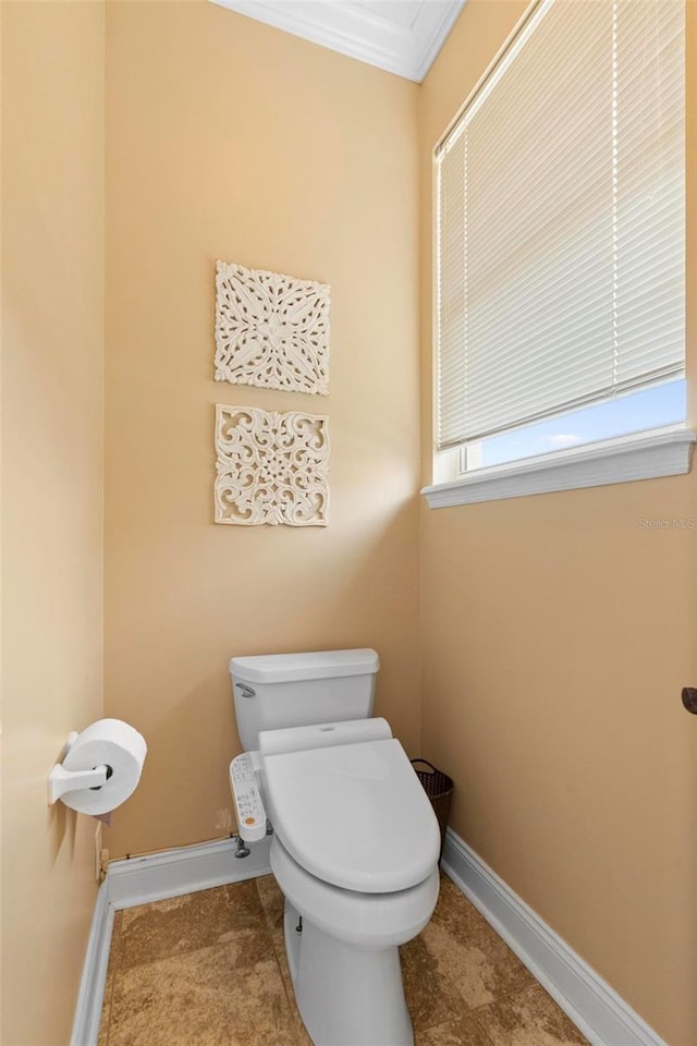 bathroom featuring tile patterned floors, crown molding, and toilet