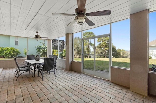 unfurnished sunroom featuring ceiling fan, wooden ceiling, and plenty of natural light