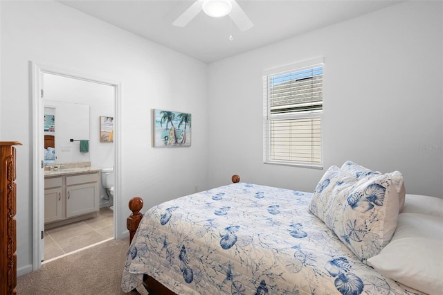 bedroom featuring ceiling fan, connected bathroom, and light colored carpet