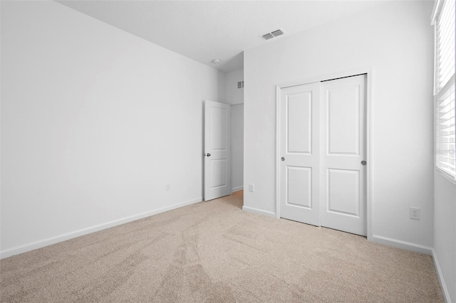 unfurnished bedroom with a closet and light colored carpet