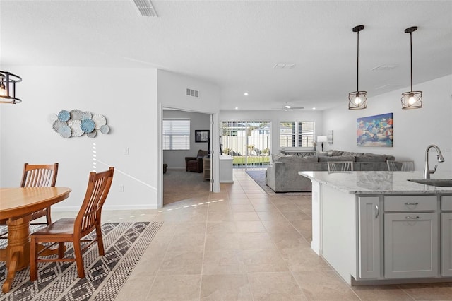 kitchen featuring decorative light fixtures, light stone countertops, sink, gray cabinets, and ceiling fan