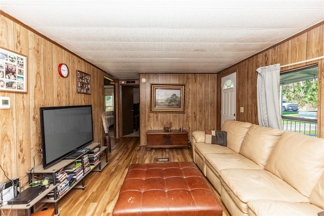 living area featuring wood walls, crown molding, and wood finished floors