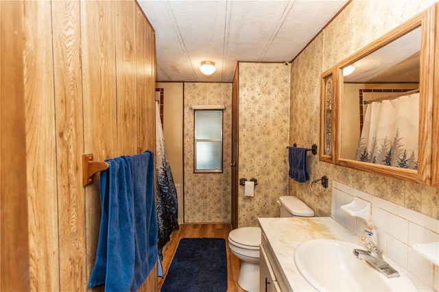 bathroom featuring wallpapered walls, vanity, toilet, and a textured ceiling