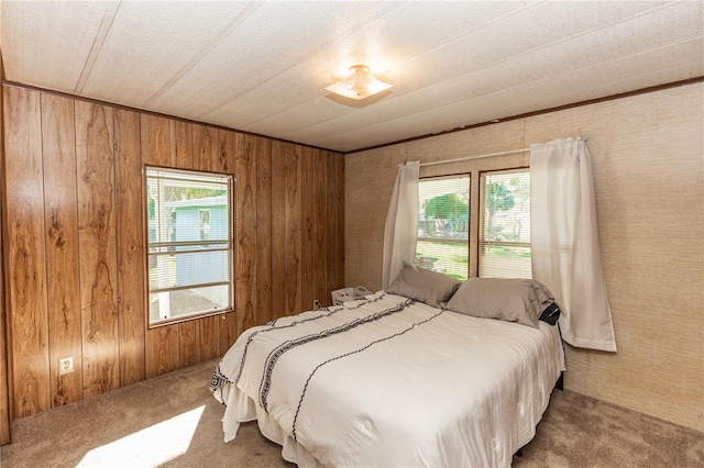 carpeted bedroom featuring multiple windows and wooden walls