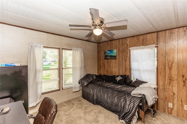 bedroom with light carpet, wood walls, and ceiling fan