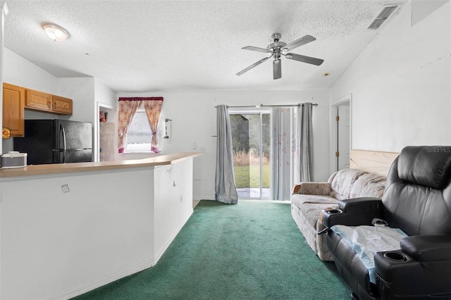 living area featuring carpet, visible vents, a ceiling fan, a textured ceiling, and baseboards