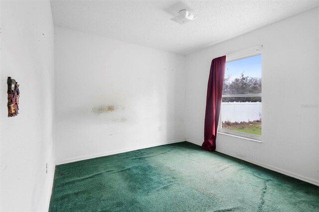 carpeted spare room with a textured ceiling and baseboards