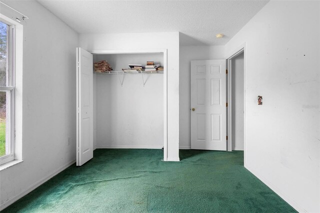 unfurnished bedroom featuring a closet, dark carpet, a textured ceiling, and baseboards