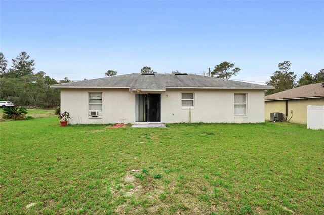 back of house with central air condition unit, a lawn, and stucco siding