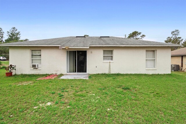 rear view of property featuring central AC, a yard, and stucco siding