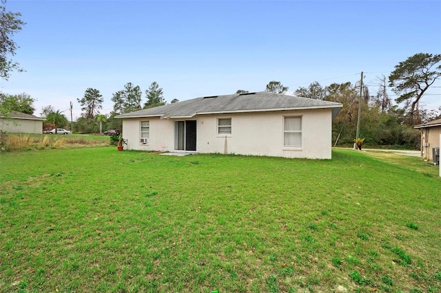 rear view of house with a lawn and stucco siding