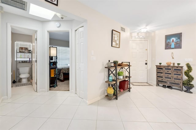 hallway with light tile patterned floors and a skylight