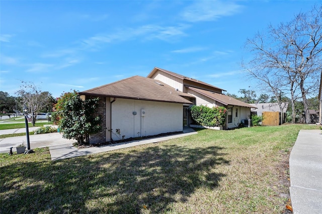 view of side of home with central AC unit and a lawn