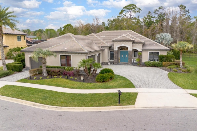 view of front of property with a tiled roof, decorative driveway, a front yard, and stucco siding