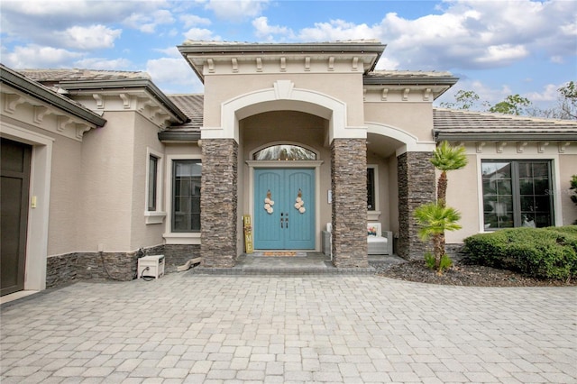 entrance to property featuring stone siding and stucco siding