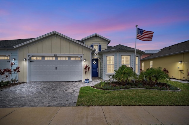 ranch-style house featuring decorative driveway, an attached garage, and a front yard