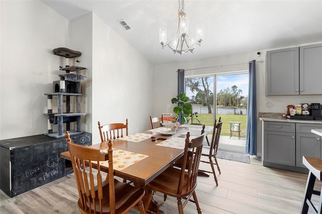 dining area with light hardwood / wood-style flooring, a notable chandelier, and lofted ceiling