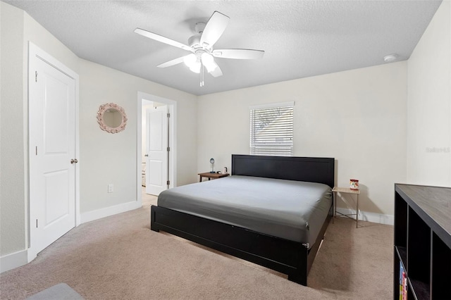 bedroom with light carpet, ceiling fan, a textured ceiling, and connected bathroom