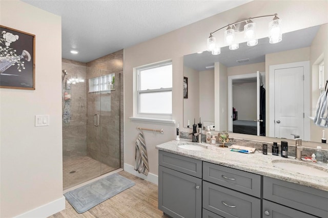 bathroom featuring a textured ceiling, wood-type flooring, a shower with shower door, and vanity