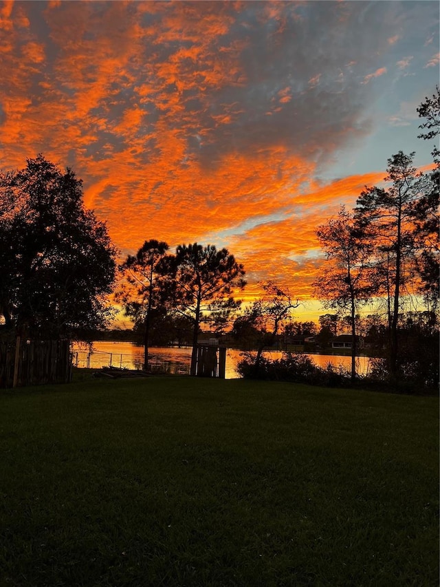 yard at dusk featuring a water view