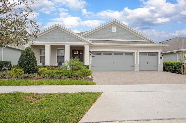 craftsman inspired home featuring a garage, decorative driveway, and stucco siding