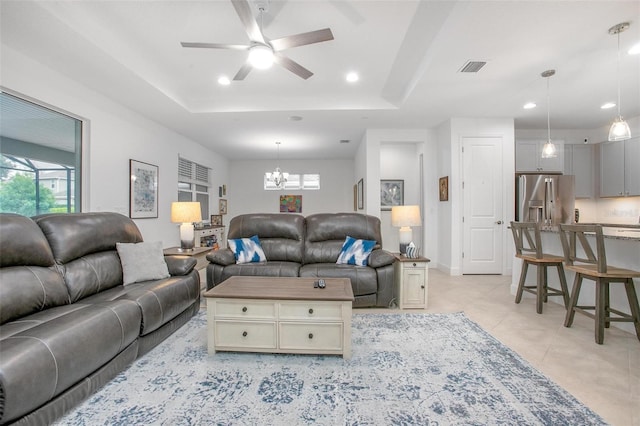 living room with light tile patterned floors, recessed lighting, ceiling fan with notable chandelier, visible vents, and a tray ceiling