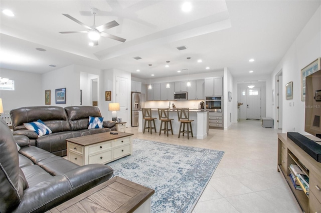 living room with recessed lighting, a raised ceiling, visible vents, light tile patterned flooring, and ceiling fan