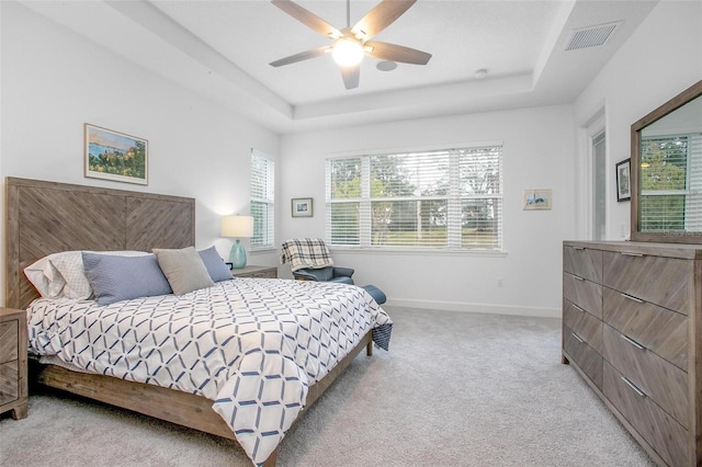 bedroom featuring light carpet, a raised ceiling, visible vents, and baseboards