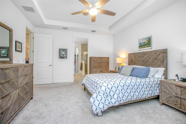 carpeted bedroom with a raised ceiling, visible vents, and a ceiling fan