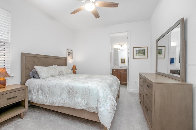 bedroom featuring light carpet, ceiling fan, and ensuite bathroom