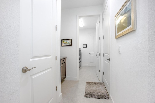 hallway featuring washer / dryer and baseboards